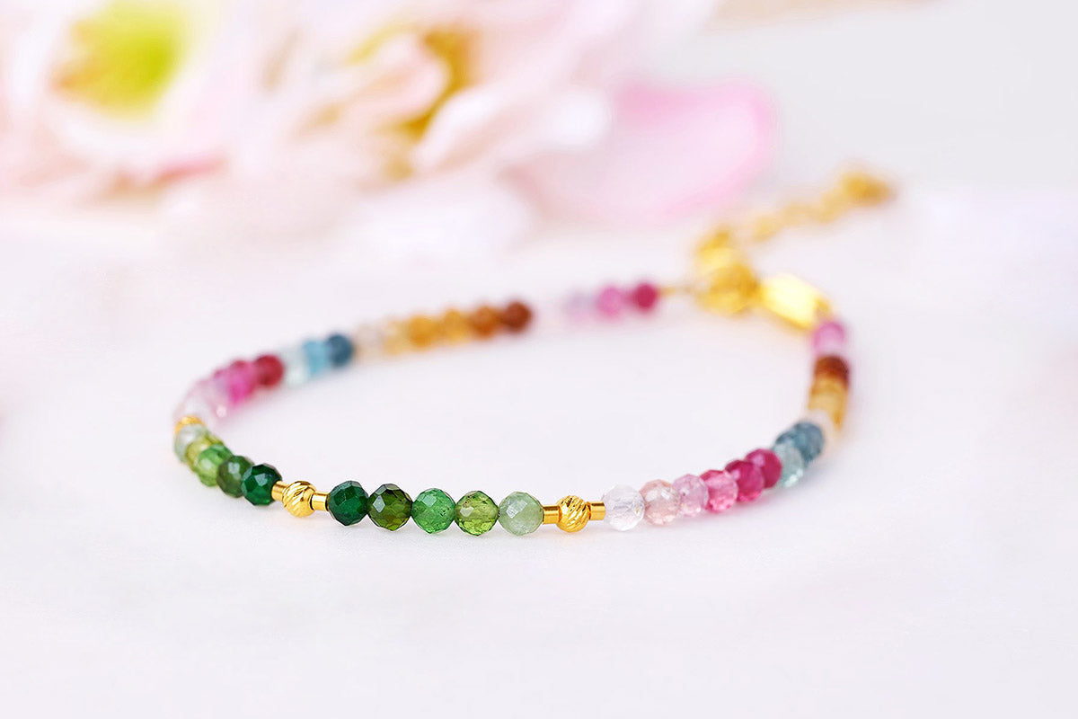 Goldener Armreif an einer Braut mit rosa Brautstrauß und weißem Hochzeitskleid als eleganter Brautschmuck.