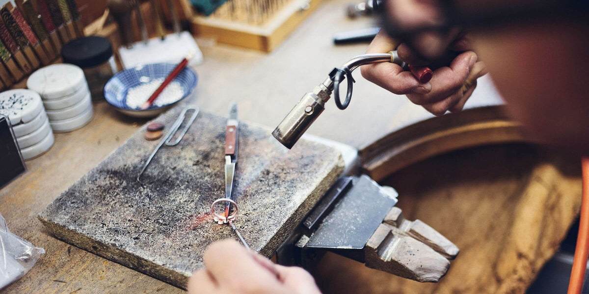 Ring wird mit einem Schmuckbrenner in der BERND WOLF Schmuckmanufaktur bearbeitet und zeigt traditionelle Goldschmiedearbeit bei der Schmuckherstellung.