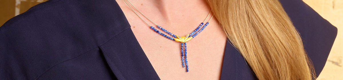 BERND WOLF Y-Collier mit blauen Edelsteinen und goldenen Elementen am Hals getragen